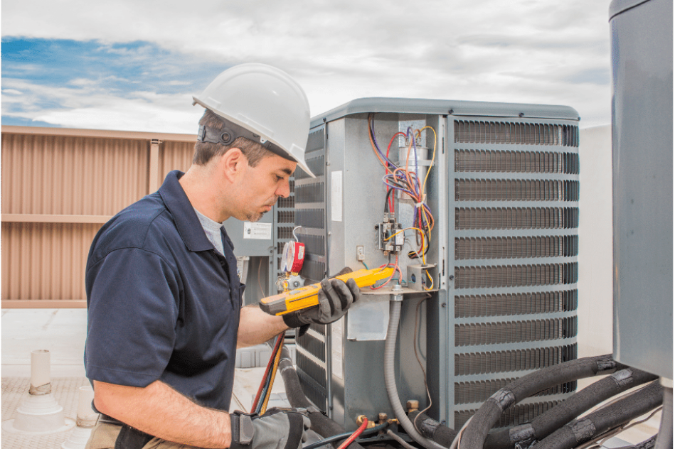 A man wearing a hard hat and gloves is working on an air conditioner.