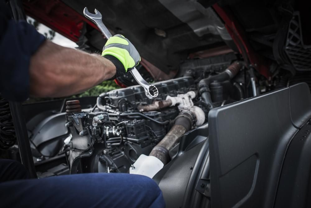 A Man Is Working on A Truck Engine with A Wrench — Lismore Car Repairs in Lismore, NSW