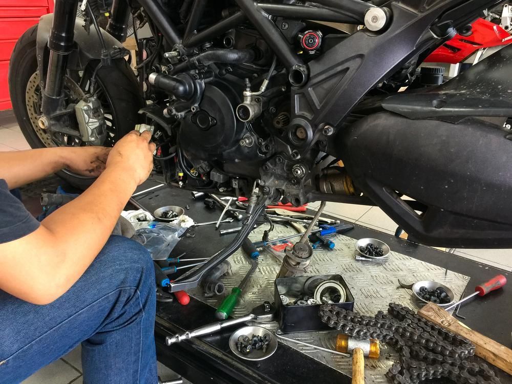 A Man Is Working on A Motorcycle in A Garage — Lismore Car Repairs in Lismore, NSW