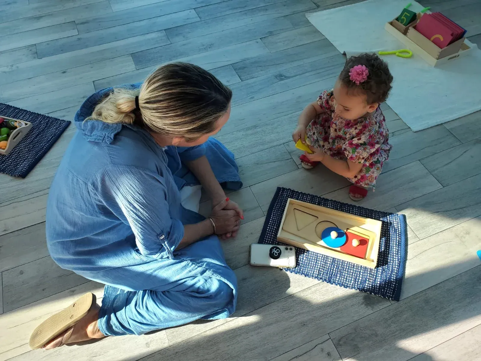 A woman and a little girl are playing with toys on the floor.