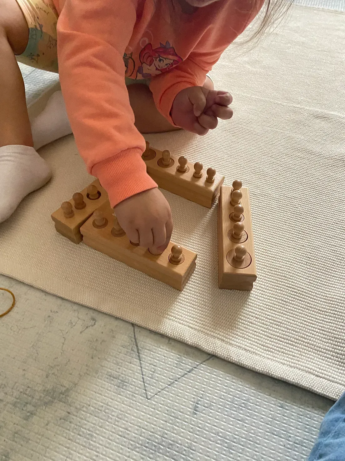 A little girl is playing with wooden blocks on the floor.