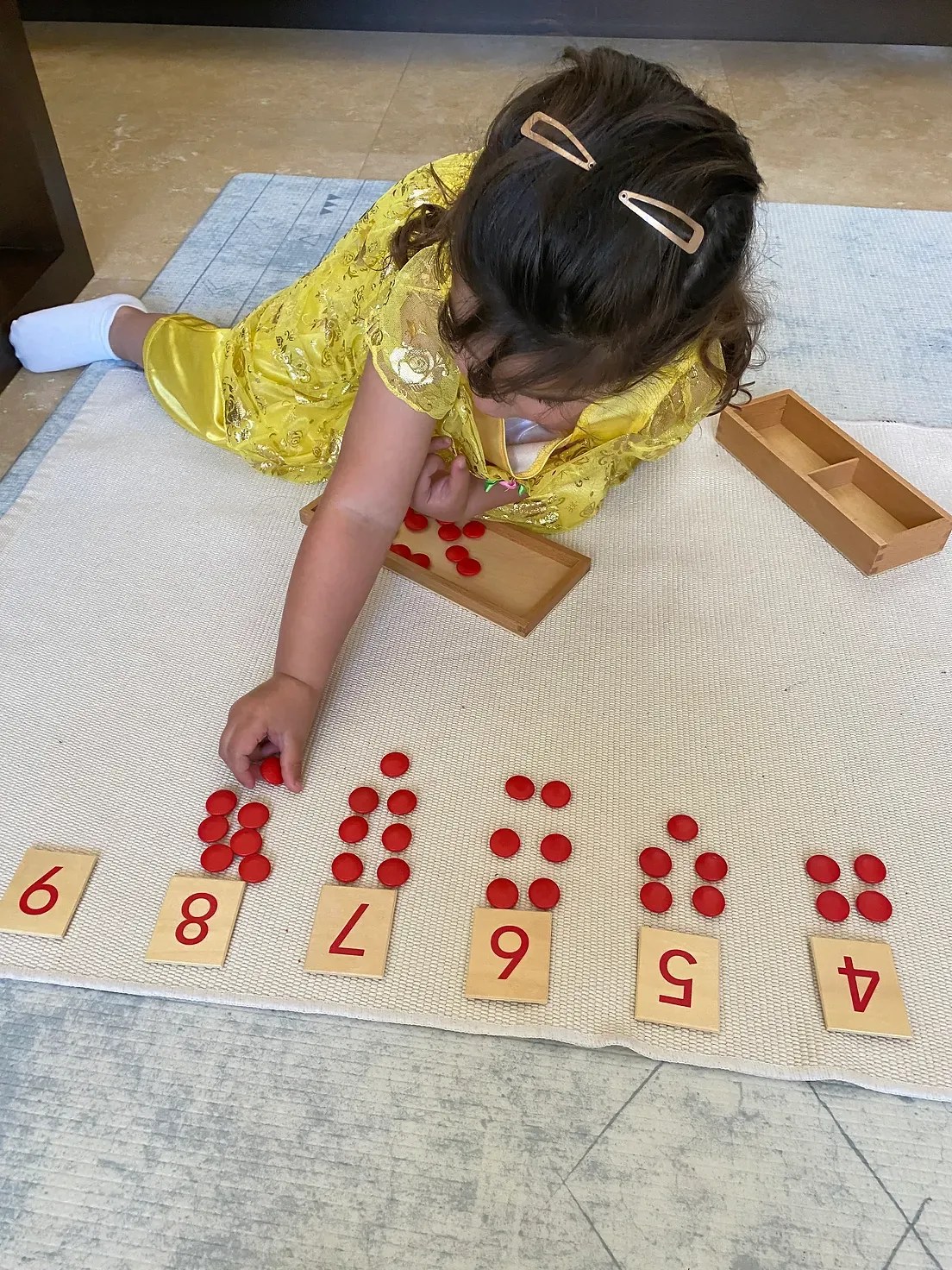 A little girl is laying on the floor playing with numbers.
