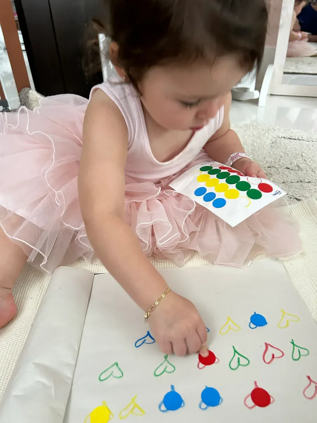 A little girl in a pink tutu is playing with stickers