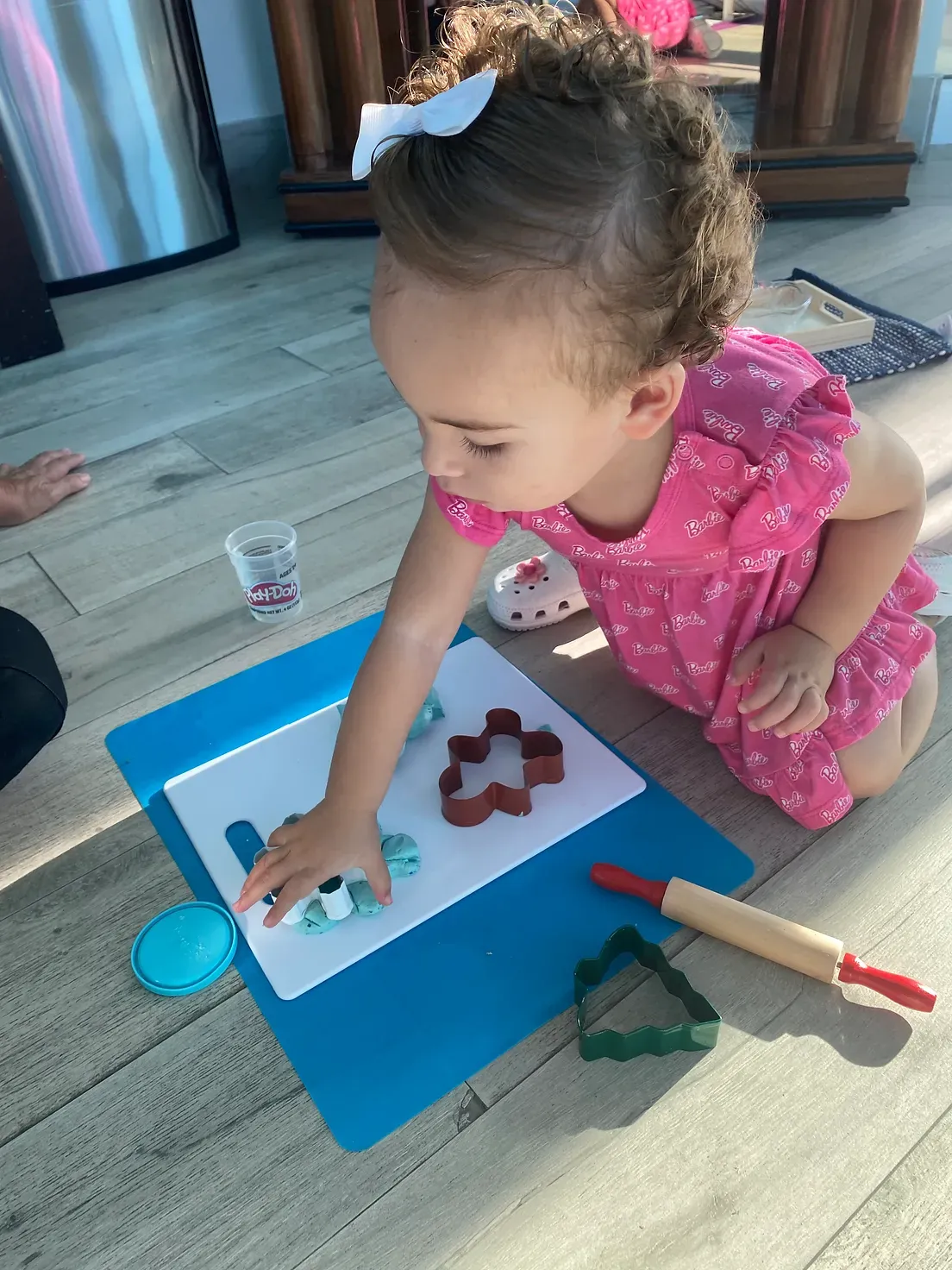 A little girl is kneeling on the floor playing with clay.