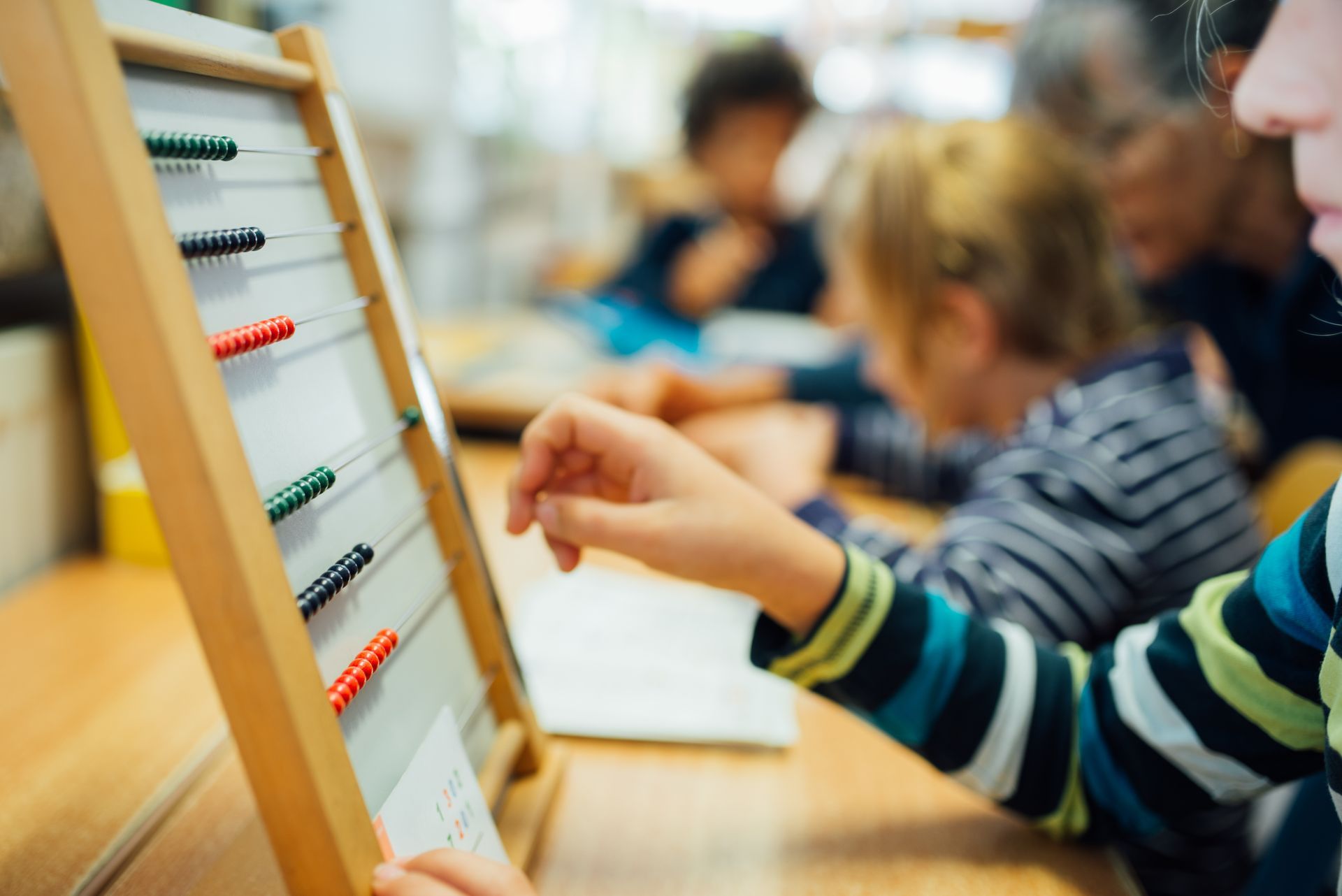 A child is using an abacus in a classroom.