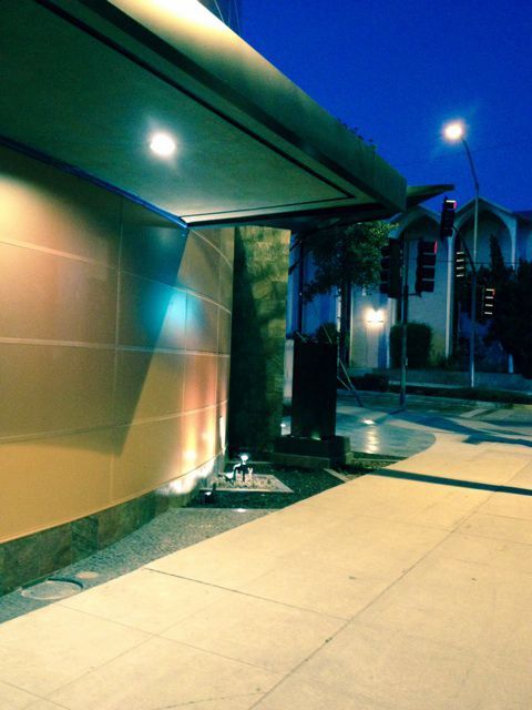 A sidewalk in front of a building at night