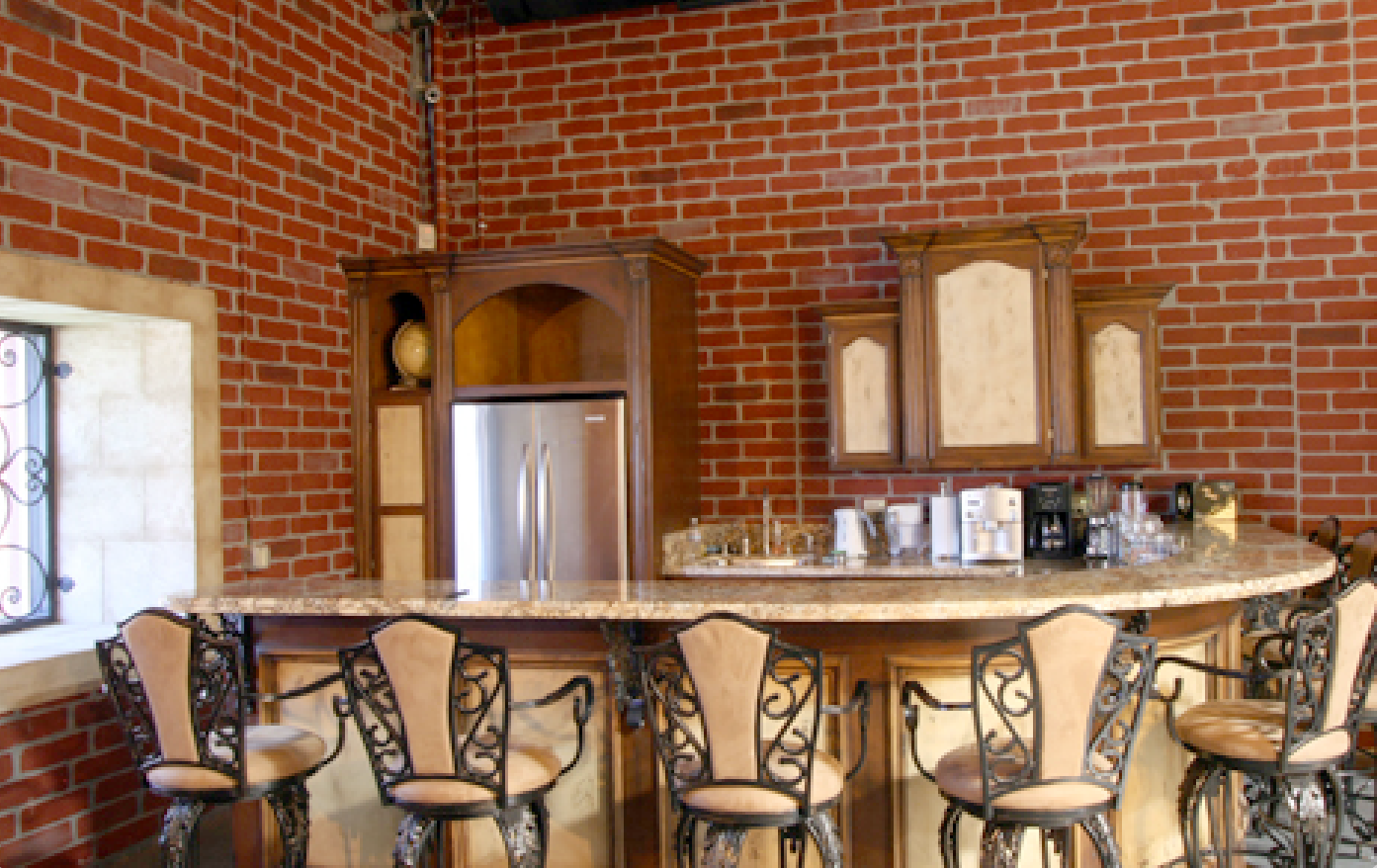 A kitchen with a bar and chairs and a brick wall.
