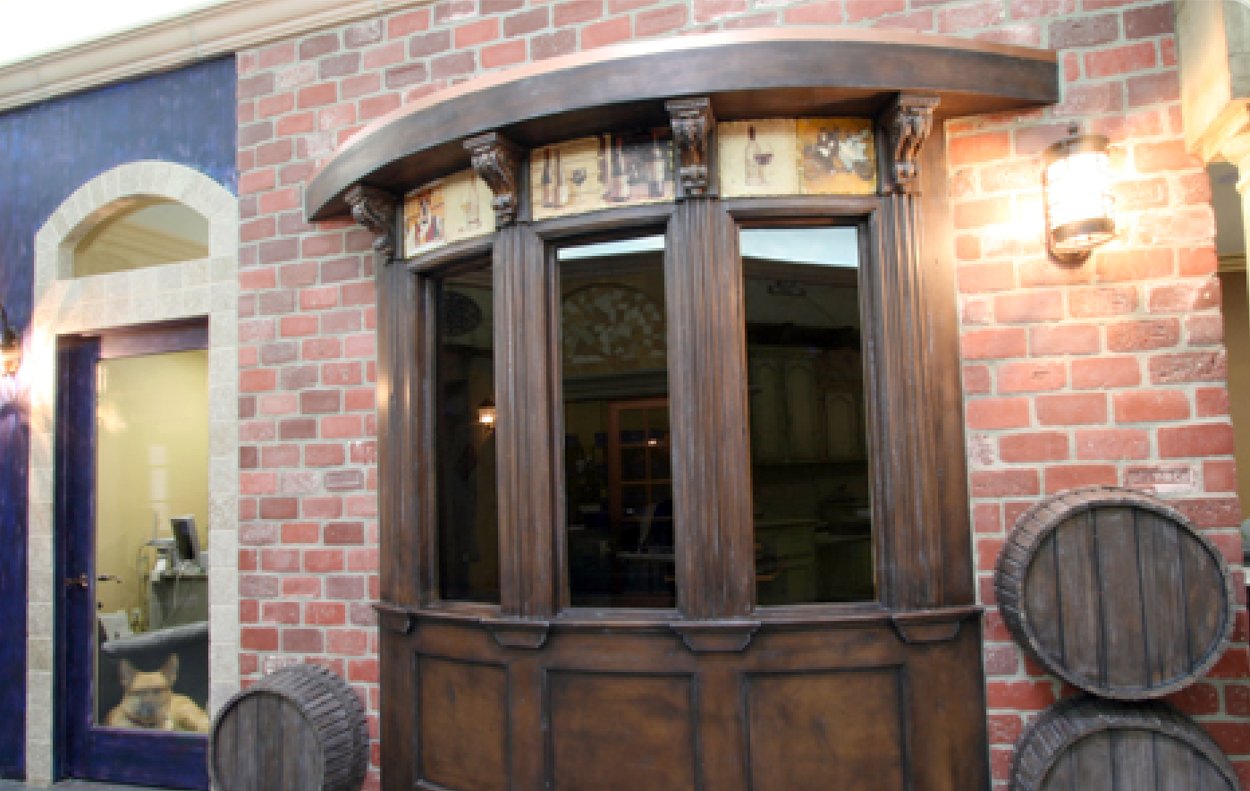 A brick building with a wooden window and barrels in front of it.