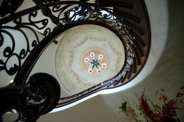 Looking up at a spiral staircase with a chandelier hanging from the ceiling