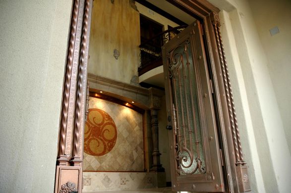 A door with a wrought iron frame is open to a room with stairs.