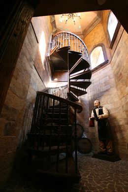 A man in a tuxedo is standing next to a spiral staircase.