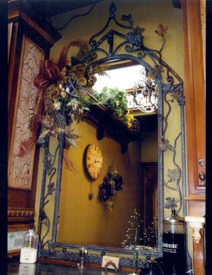 A wrought iron mirror with a clock on the wall behind it