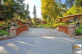 A cobblestone driveway leading to a house with a bridge over it.