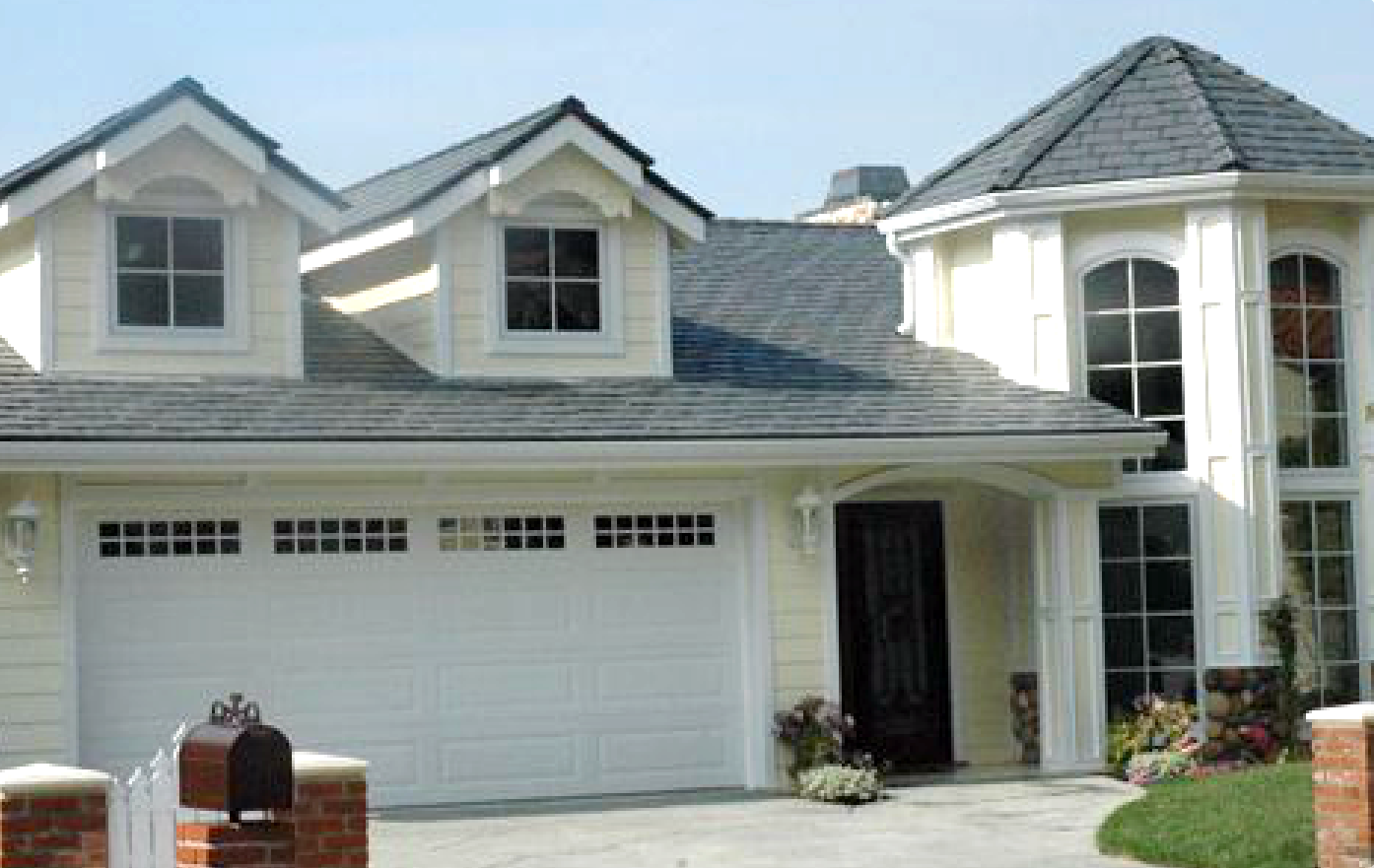 A white house with a gray roof and a white garage door