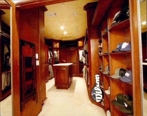 A walk in closet with a wilson racket on the shelf