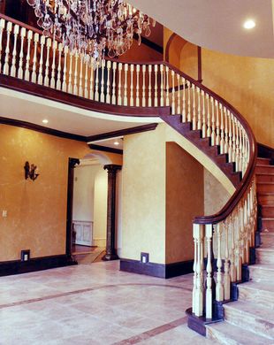 A curved staircase with a chandelier hanging from the ceiling