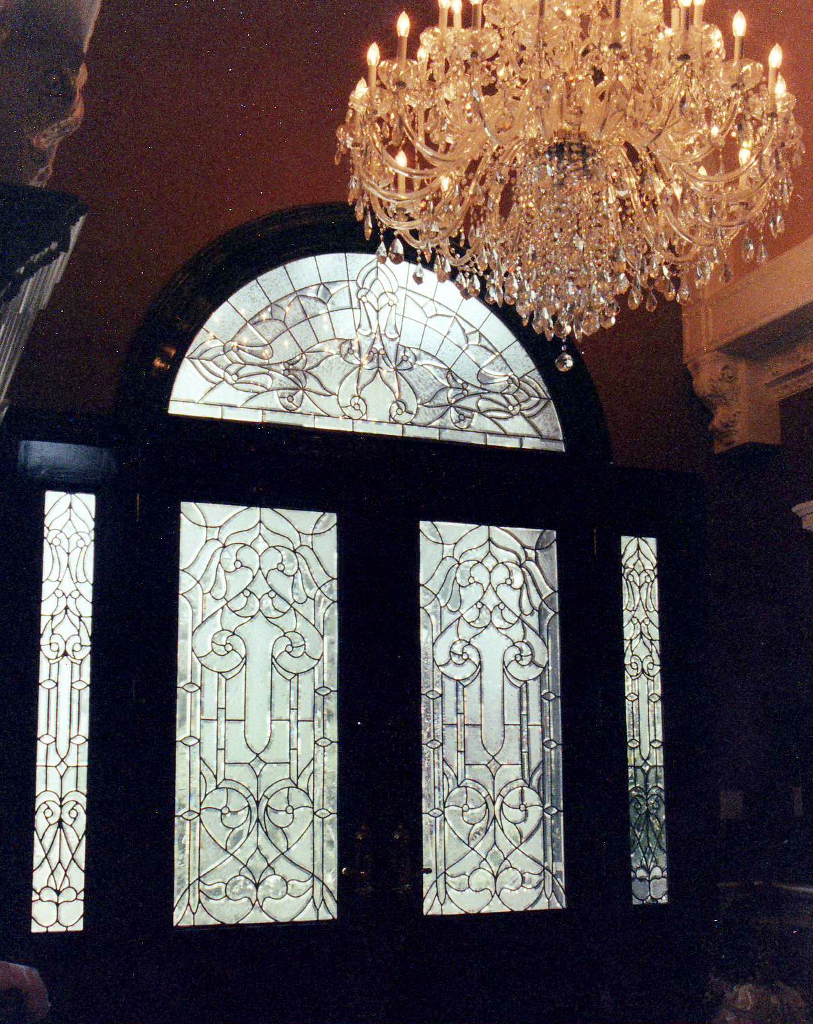 A stained glass door with a chandelier above it