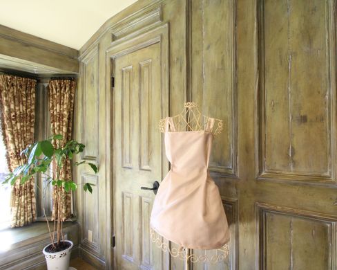 A pink dress is hanging on a mannequin in a room.