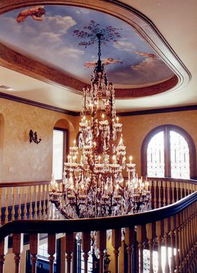 A large chandelier hangs from the ceiling above a staircase