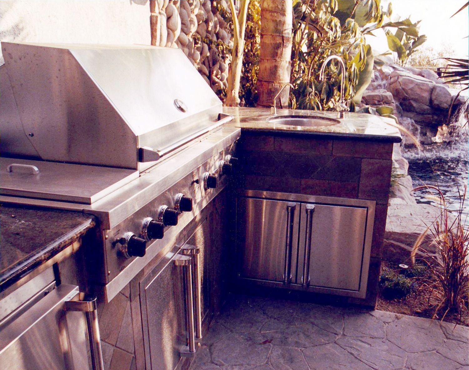 An outdoor kitchen with stainless steel cabinets and a grill