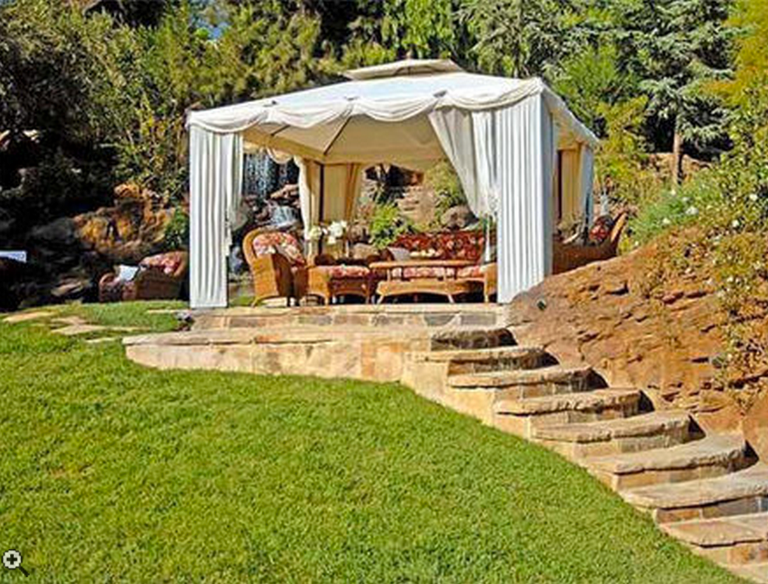 A white tent is sitting on top of a lush green lawn next to stairs.