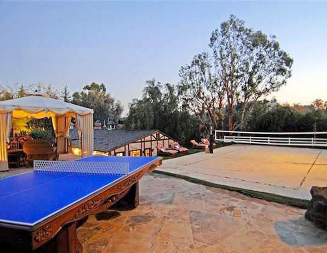 A blue ping pong table is sitting on a patio next to a pool table.