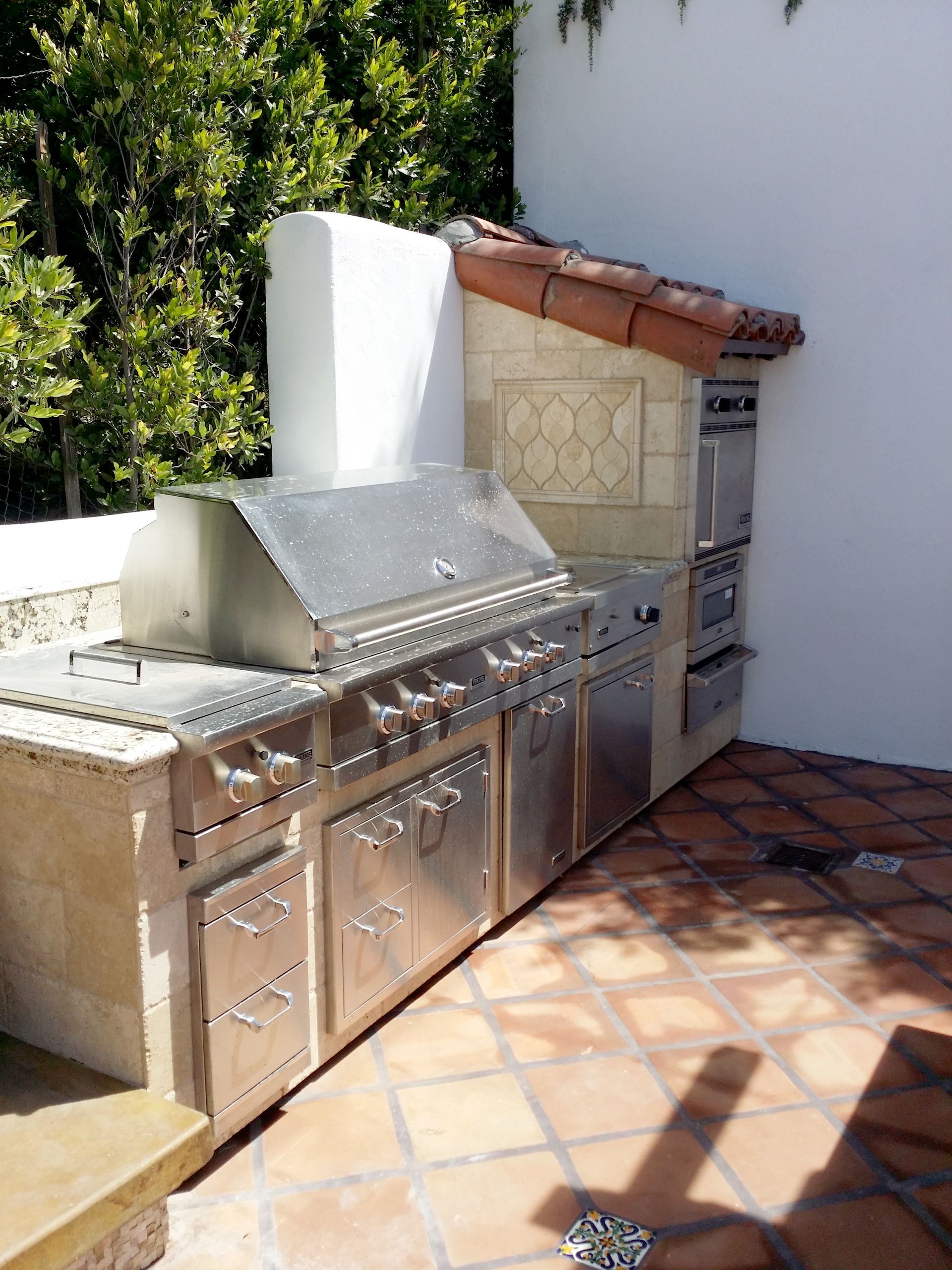 An outdoor kitchen with stainless steel cabinets and a grill