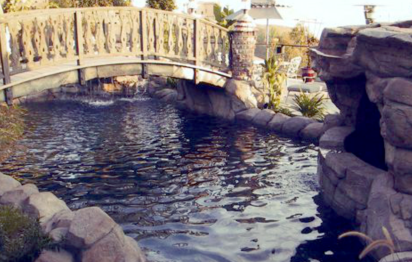 A bridge over a pond with a waterfall in the background
