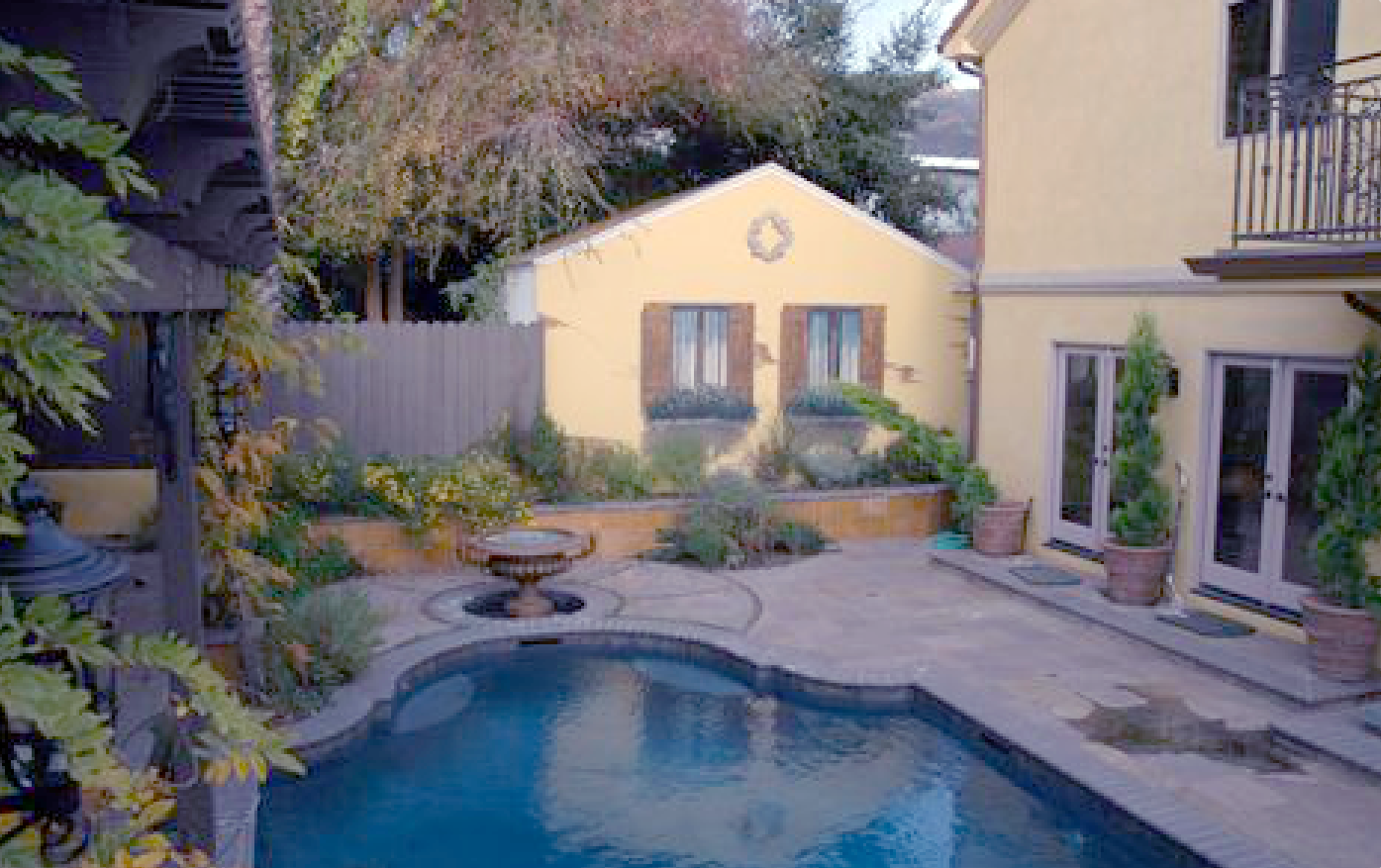 A large swimming pool is in the backyard of a house.