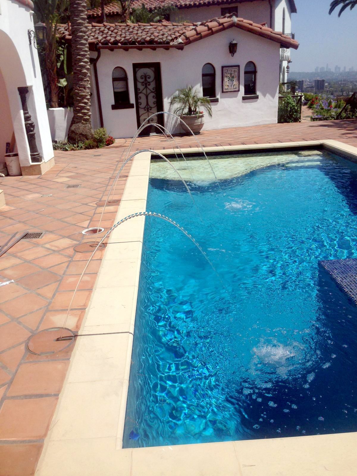 A large swimming pool in front of a white house