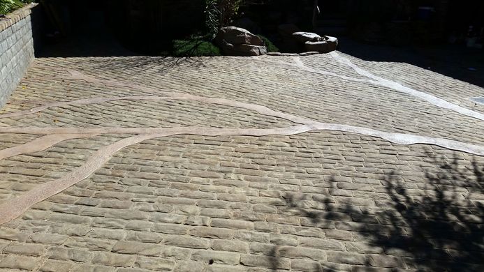 A cobblestone driveway with a brick wall behind it.