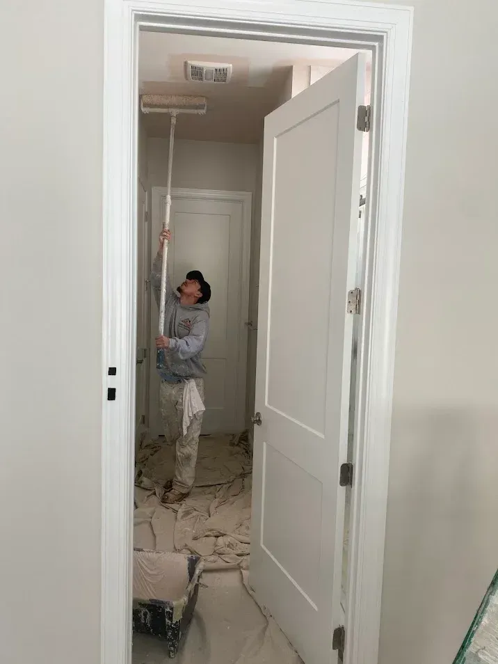 Two painters from Oasis Painting & Drywall LLC working in Philadelphia, PA, painting a room with white and  green