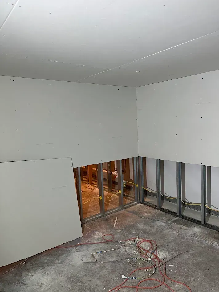 Drywall sheets staged against a wall before installation in a home renovation project in Drexel Hill, PA.