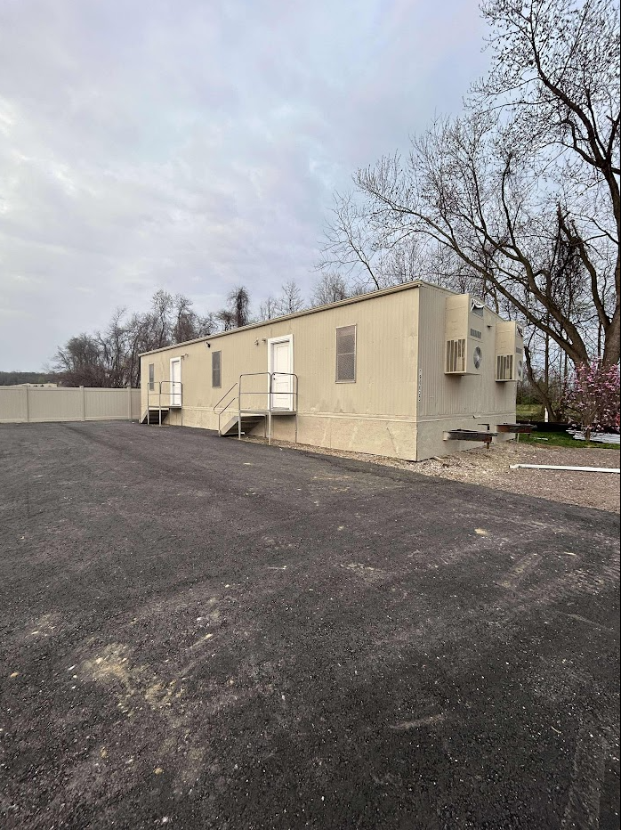 A mobile home stands in the middle of a parking lot that has been painted cream.