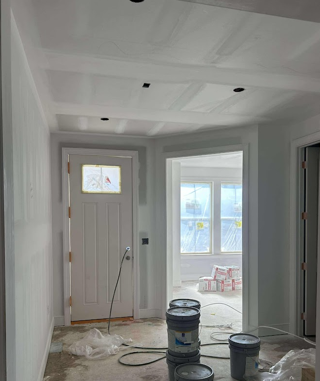 A hallway in a house under construction with buckets of paint on the floor.