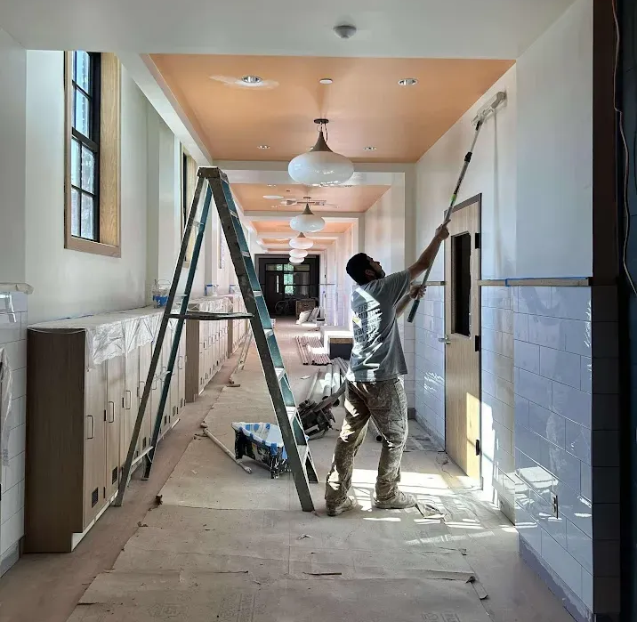 Harrisburg PA school painting – professional painter with roller on wall and orange ceiling by Oasis Painting & Drywall.