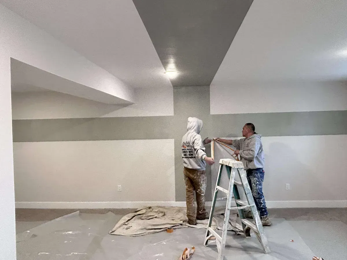 Chester PA interior painting – painters working on green cross over white wall by Oasis Painting & Drywall