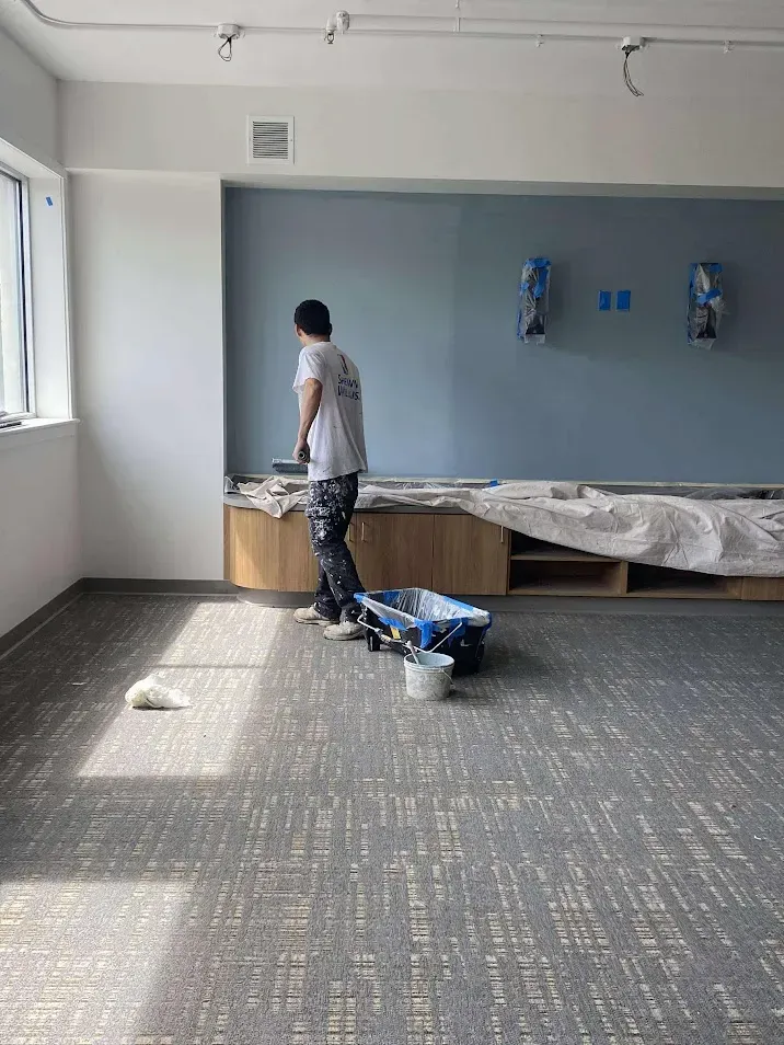 North Wales PA office painting – professional painter rolling blue wall in dining area by Oasis Painting & Drywall.