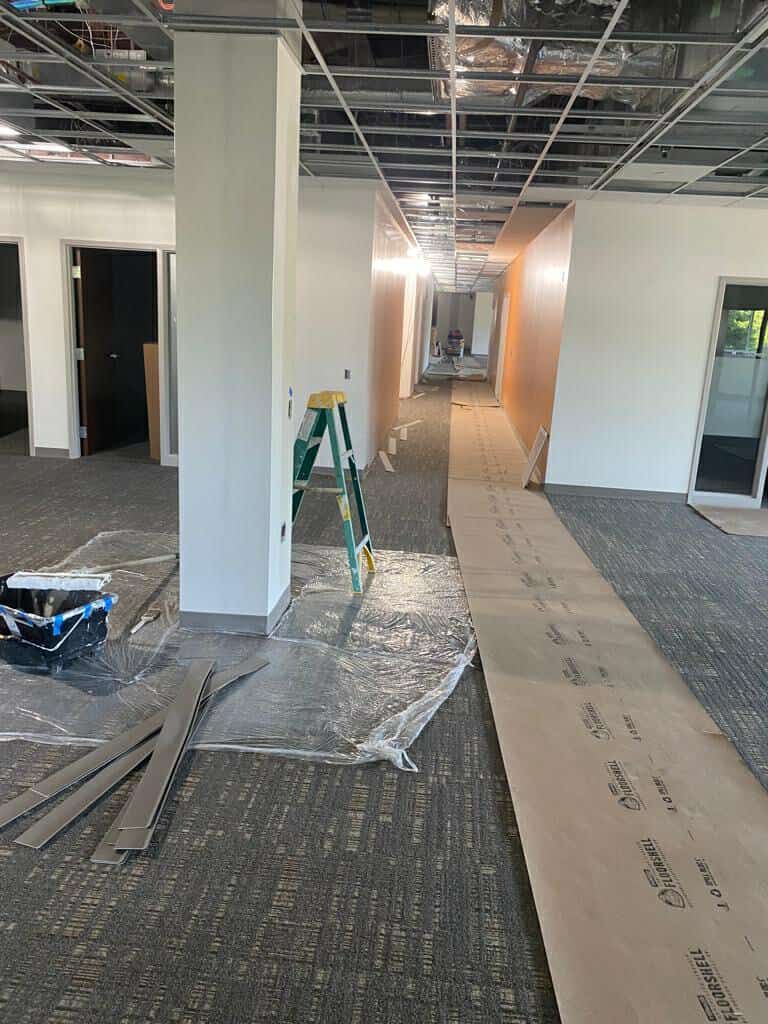A long hallway being painted, with a staircase in the middle.