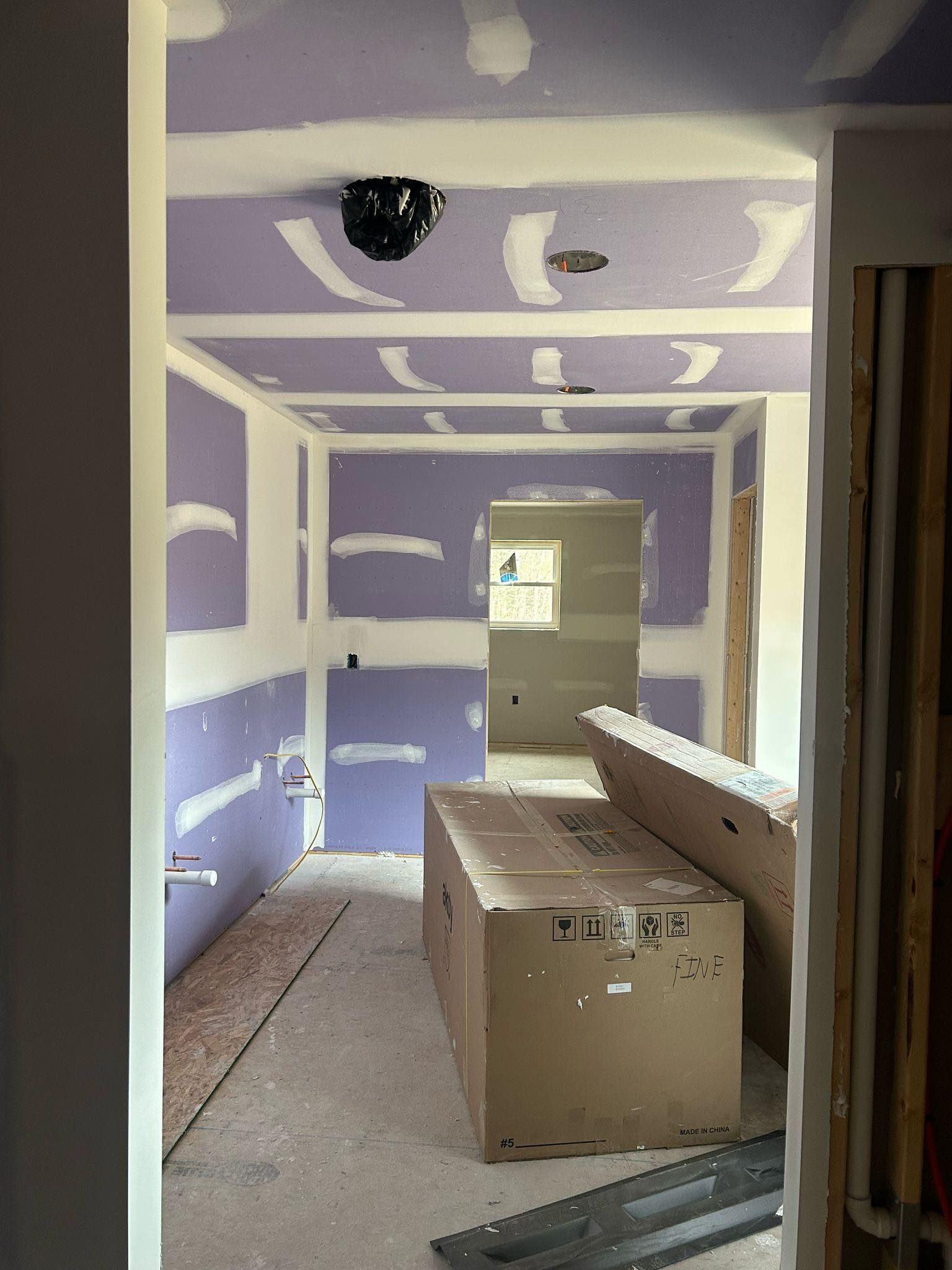 A room with purple walls and white trim is being remodeled.