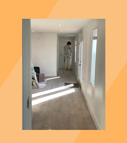 Ambler PA interior painting – painter on ladder painting hallway walls white by Oasis Painting & Drywall.