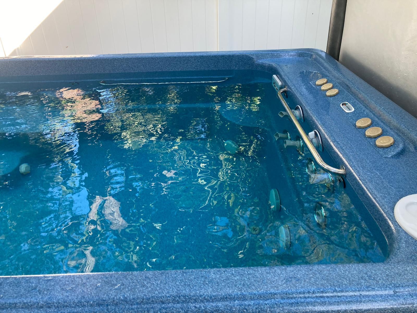 Blue hot tub filled with water and debris; control panel on the side.