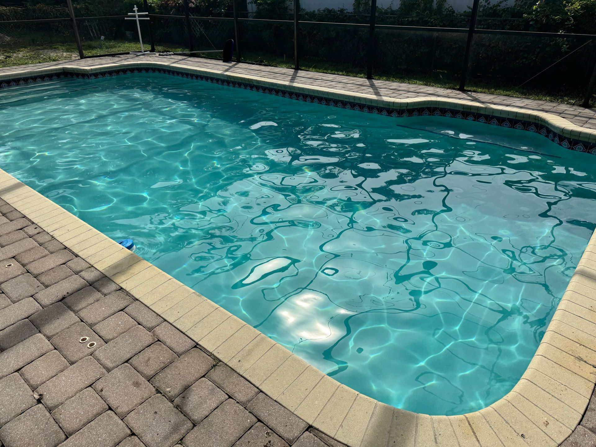 Swimming pool with clear turquoise water and brick patio.