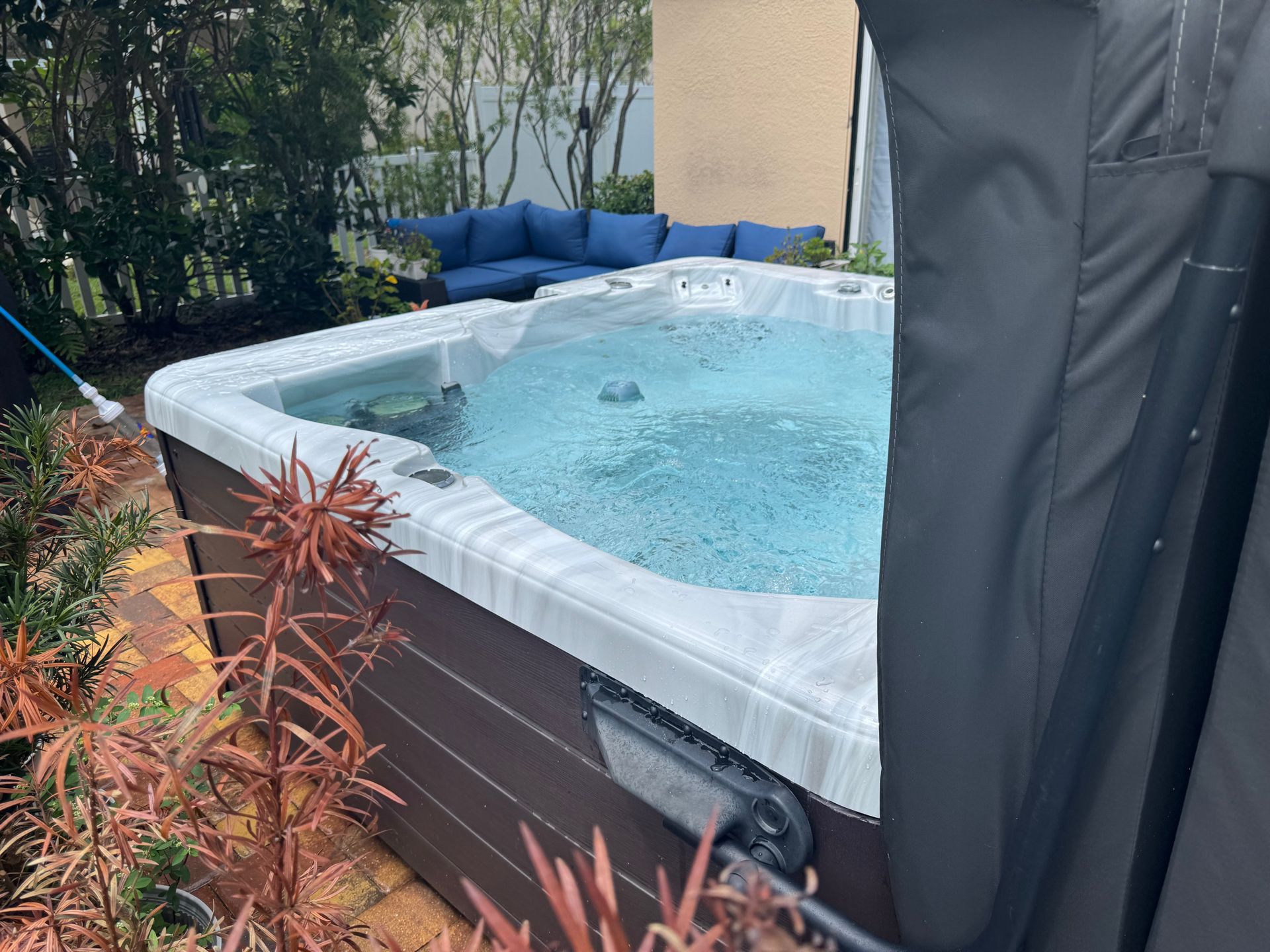 Hot tub with bubbling water, surrounded by plants and outdoor seating.