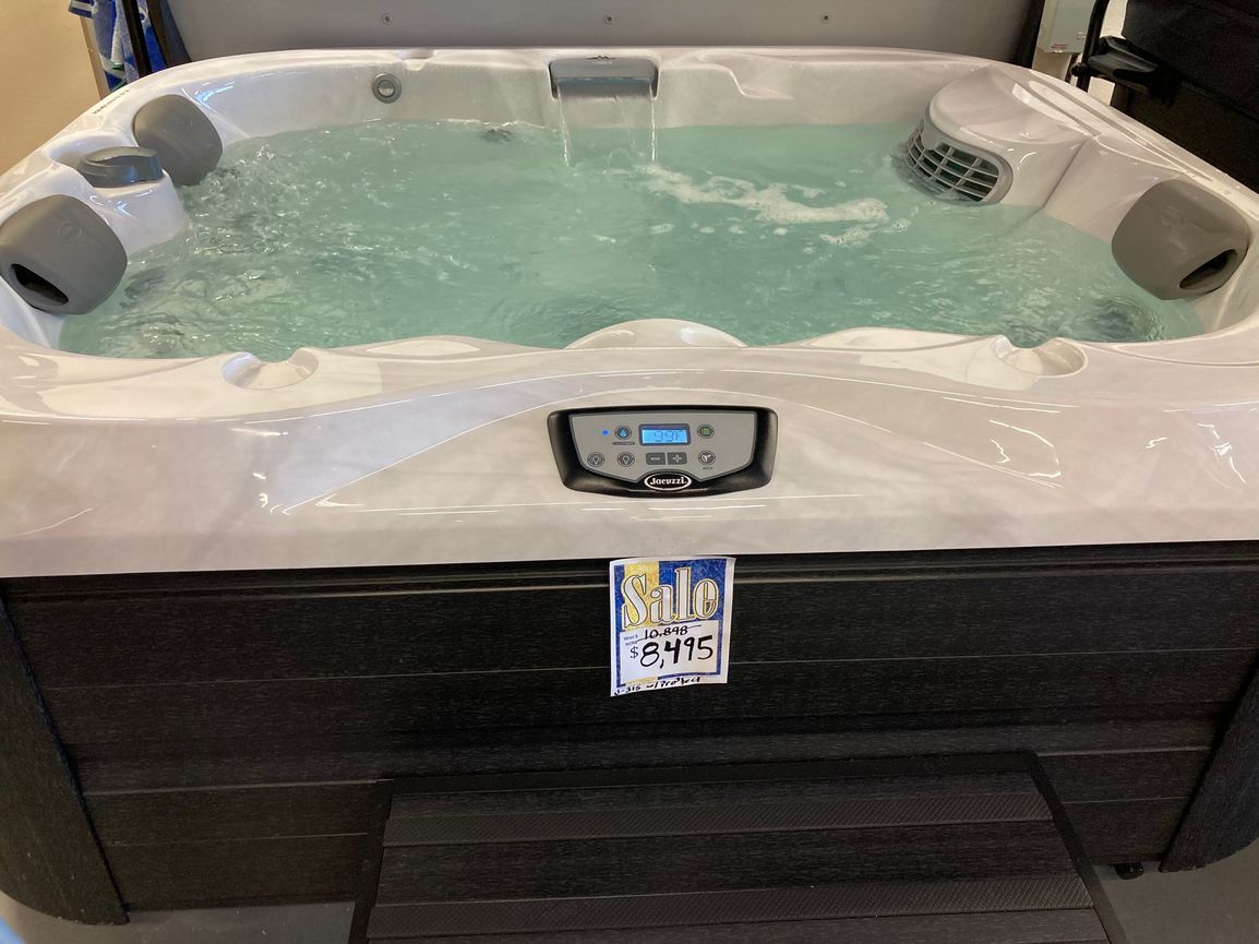Hot tub filled with water, with a control panel, water features, and steps visible.