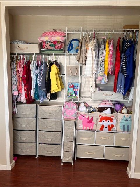 Closet organization with hanging clothes, drawers, and storage bins.