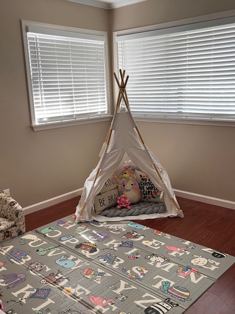 Child's playroom with a teepee, ABC play mat, and a window.