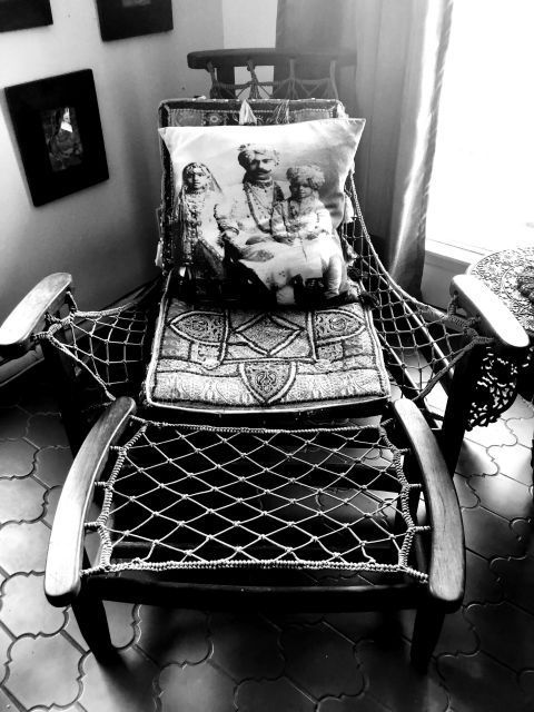 Wooden armchair with woven seat, decorative cushion, and net detail.
