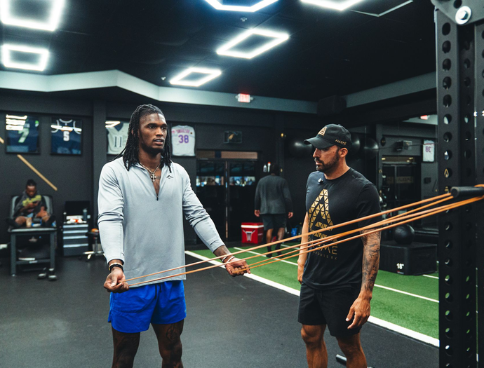 Shirtless athlete working out with resistance band in gym.