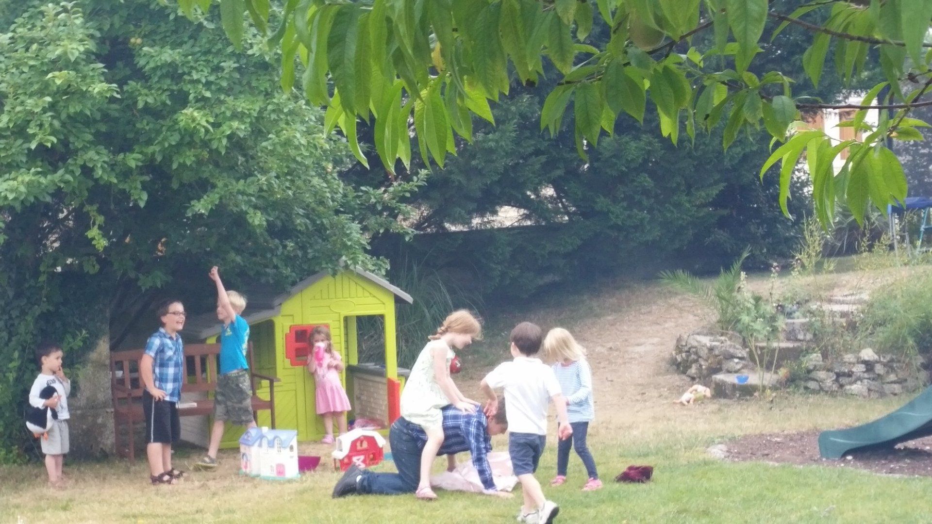 children playing in a garden outside a green playhouse